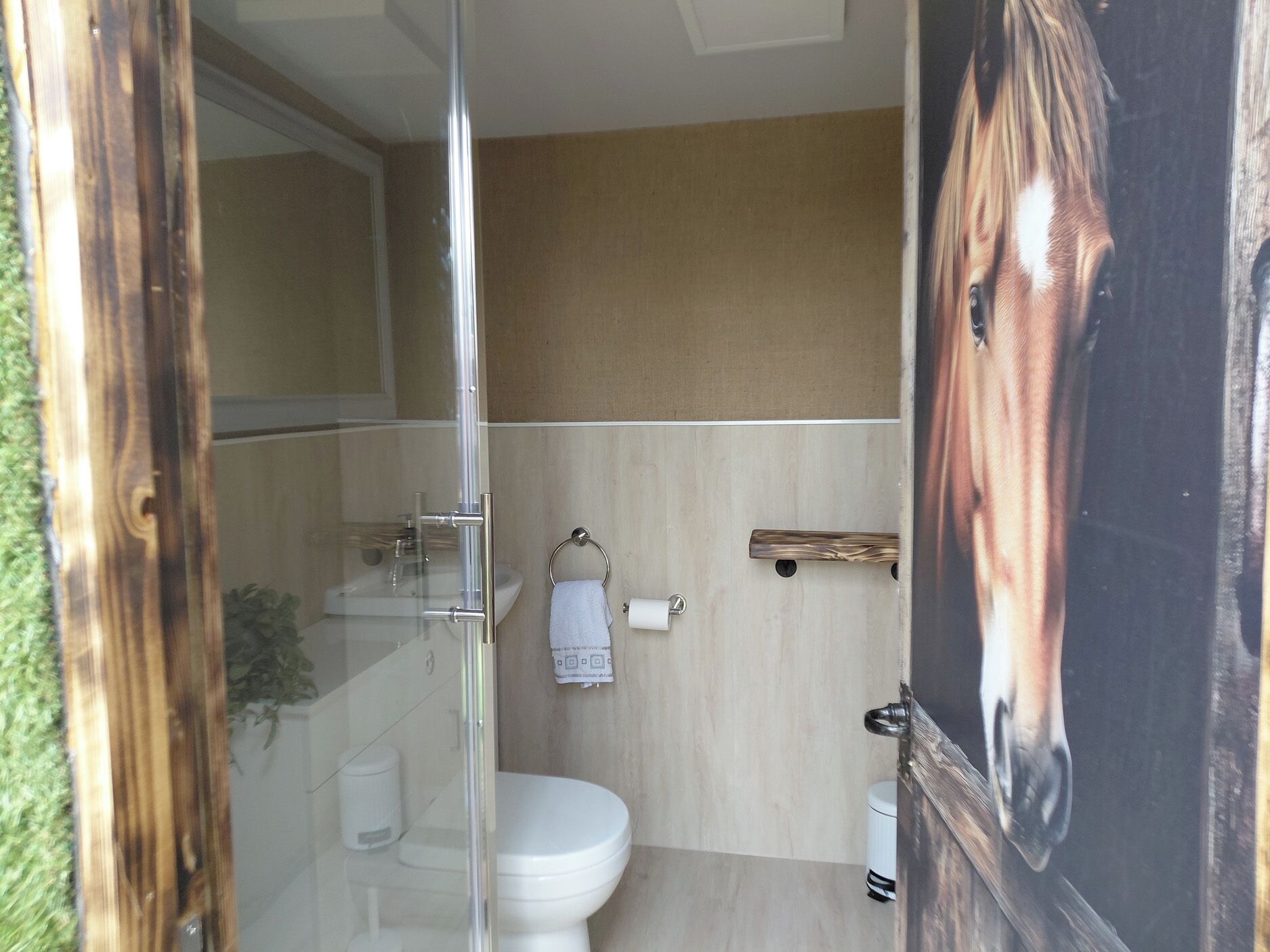 Un baño con cabina de ducha de vidrio, inodoro, lavamanos y toallero.