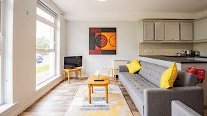 A living room with a sofa, a coffee table, a TV, and a painting on the wall. - Cozy 2-Bedroom Apartment in Galway (Galway)