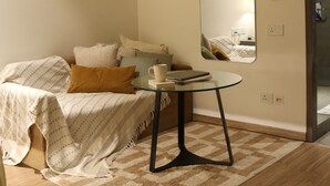 Une chambre à coucher avec un lit, une table ronde, un miroir et des œuvres d’art accrochées au mur.
