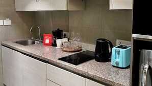 Une cuisine moderne avec des meubles de couleur bois clair, un évier en acier inoxydable, une machine à café, un grille-pain et une bouilloire.