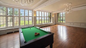 A spacious room with a pool table, large windows, and a chandelier. - Hanlith Hall (Skipton)