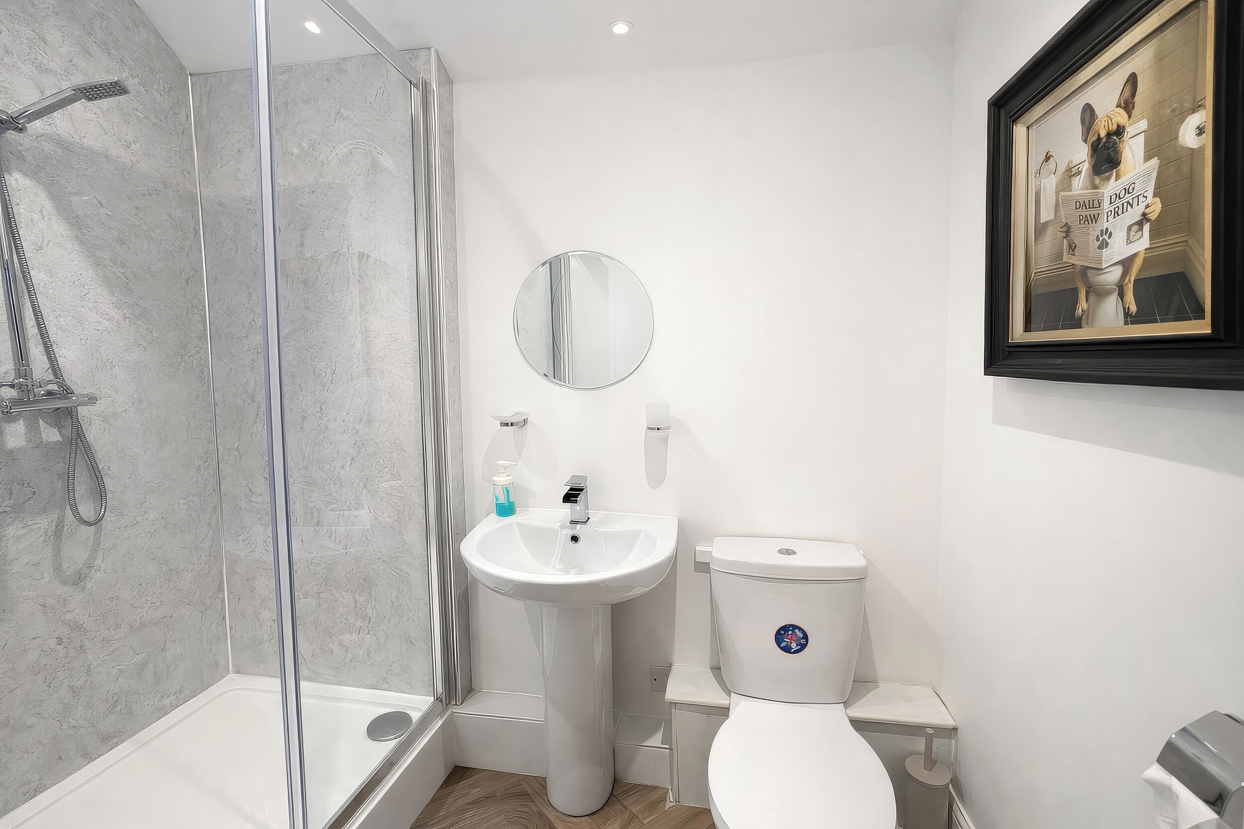 A modern bathroom with a glass-enclosed shower, a pedestal sink, and a toilet.