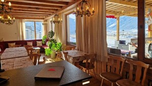 Un restaurante con interiores de madera, ventanas amplias y vistas a las montañas.