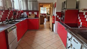 Una cocina con armarios rojos, lavavajillas y microondas.