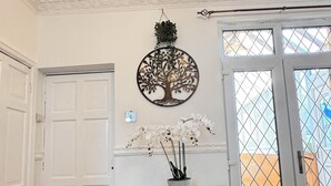 Una habitación con un armario de madera, un colgador decorativo con forma de árbol y vistas a través de un ventanal.