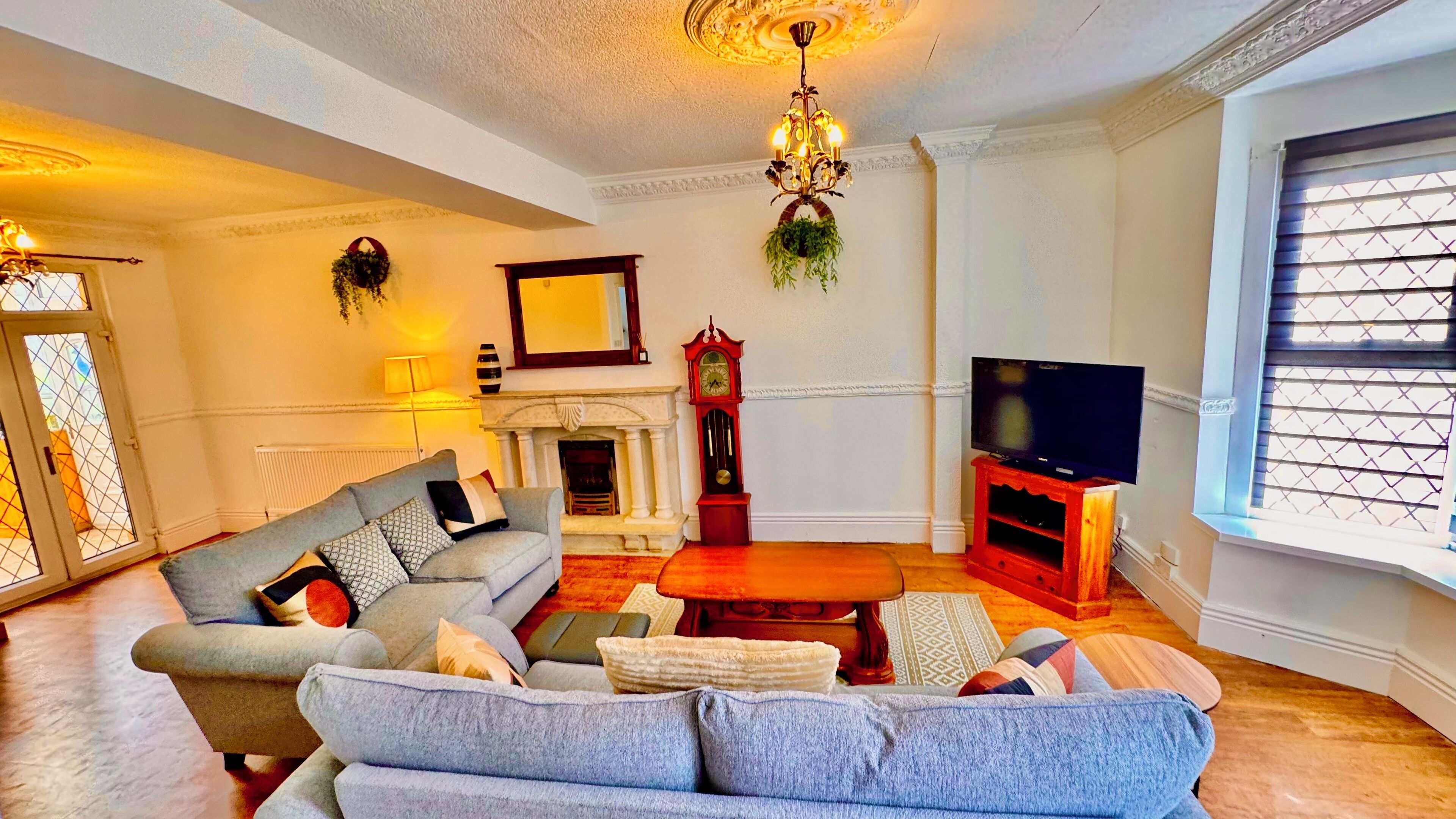 A living room with a sofa, a television, a fireplace, and a clock.