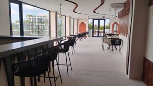 Et moderne barområde med høje lofter, store vinduer og udsigt til det fri.