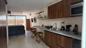 Et moderne køkken med træskabe, indbygget mikrobølgeovn og en bordplade med en blender og kaffemaskine.