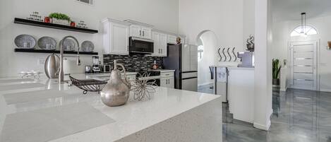 Una cocina moderna con armarios blancos, una isla central y un salpicadero negro.