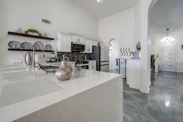A modern kitchen with white cabinetry, a central island, and a black backsplash. - < 1 Mi to Talking Stick Amp! Family Escape w/ Pool (Phoenix)