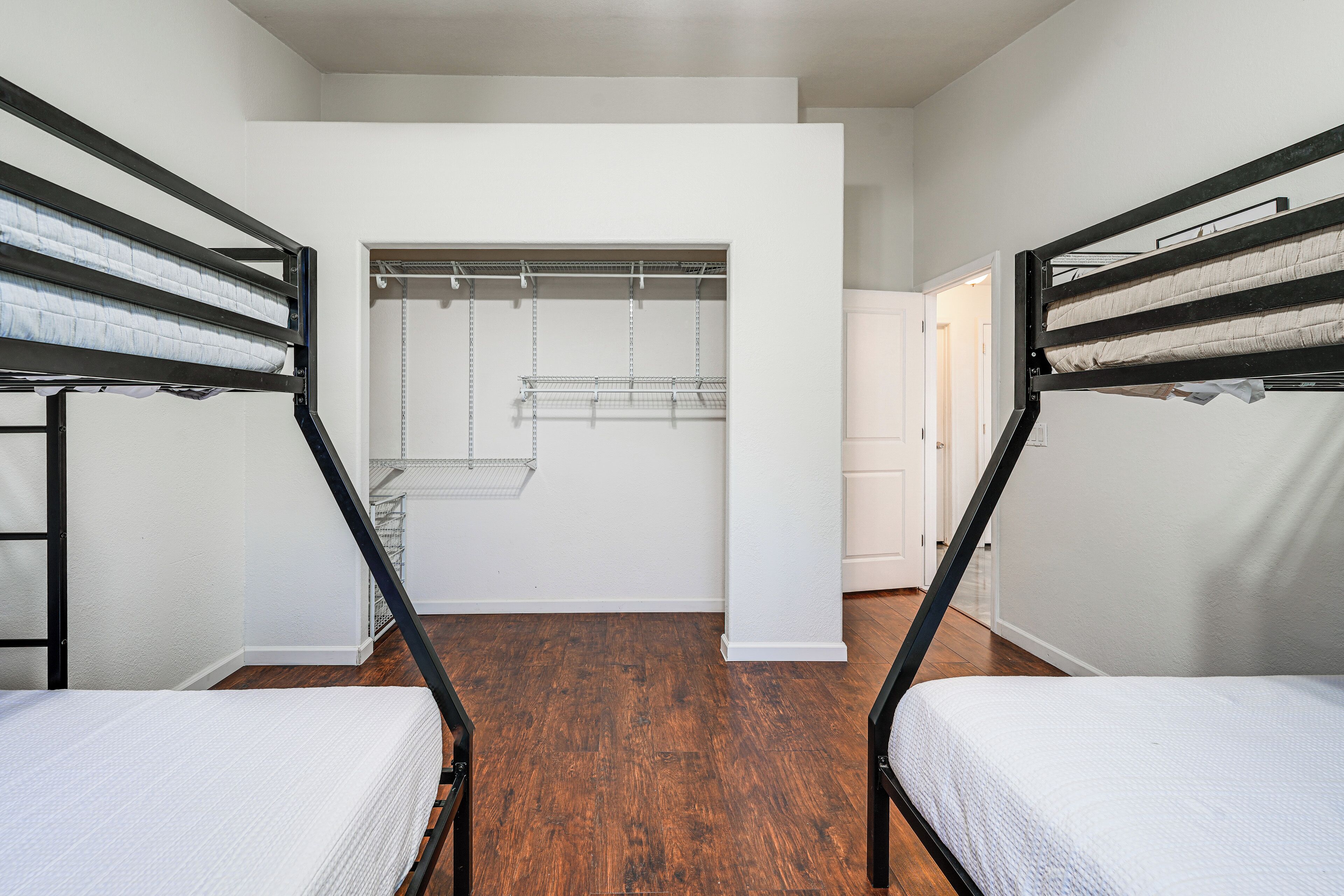 A room with bunk beds, a walk-in closet, and wooden flooring.