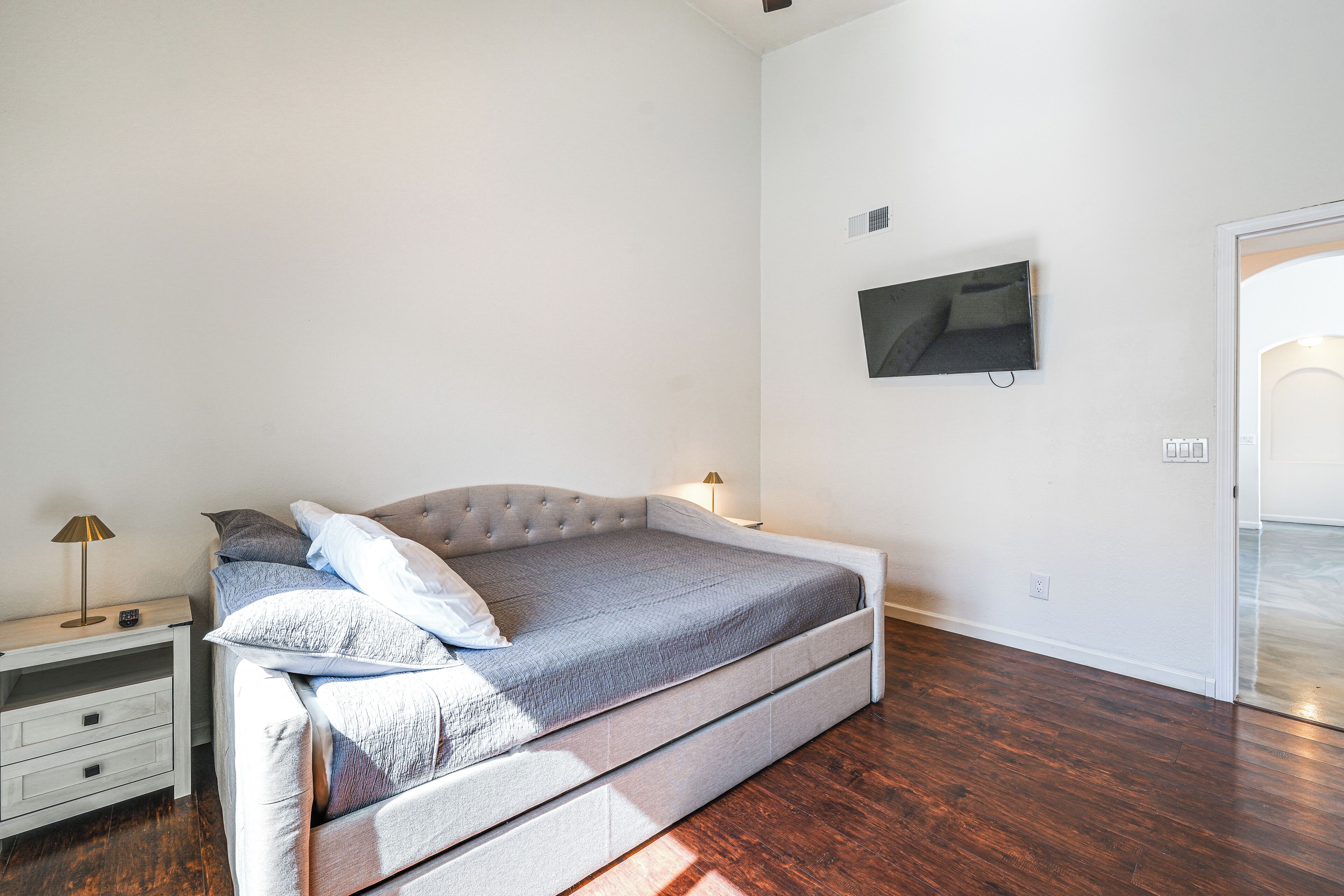 Una camera da letto con un letto, un comodino, una lampada e un televisore appeso alla parete.