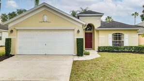 A single-story house with a white garage door, a red front door, and a small porch with a window. - 11 Mi to Disney! Family Haven w/ Poolside Oasis (Davenport)