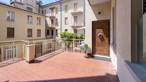 Un immeuble résidentiel doté d’un balcon, d’une porte en bois et d’une plante en pot.