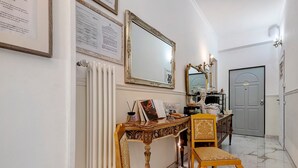 Un couloir avec un radiateur, un miroir, un certificat encadré et une porte.