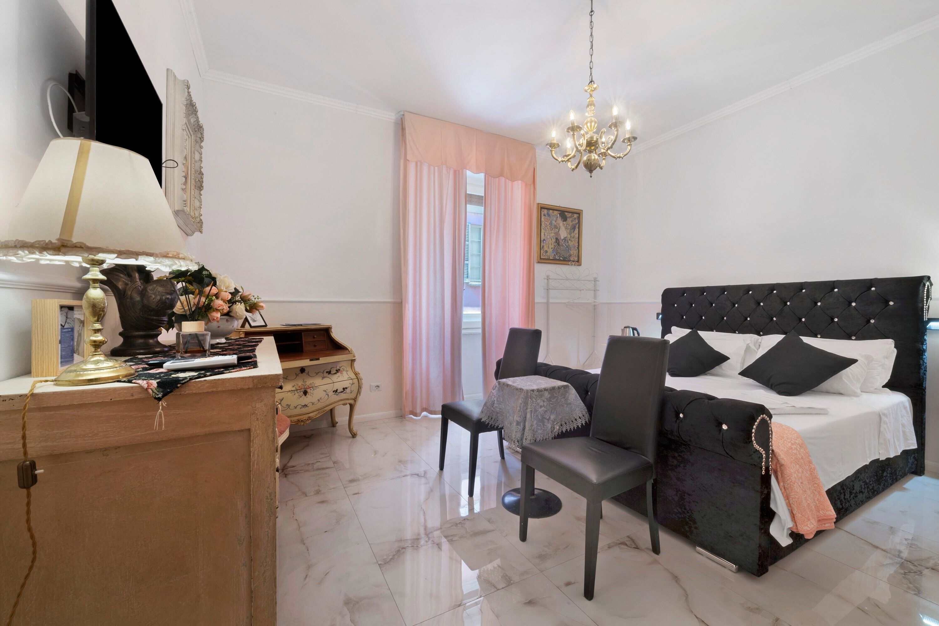Un dormitorio con cama, escritorio, silla, candelabro y ventana con cortinas.