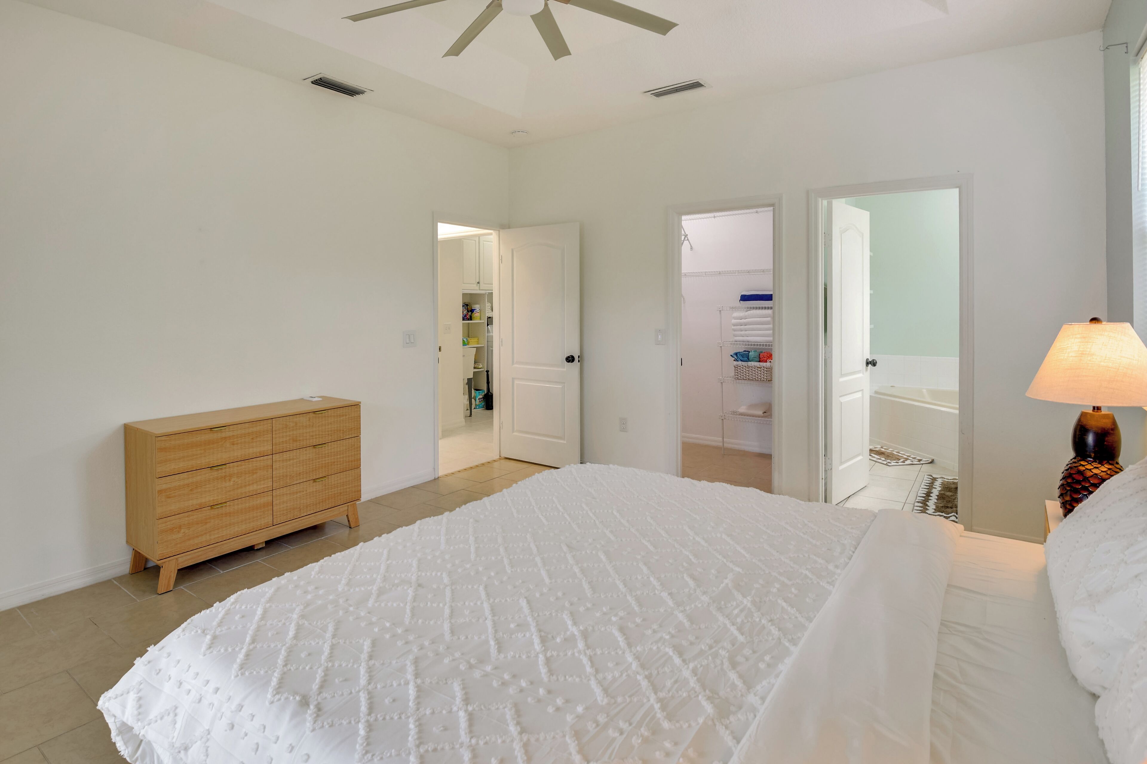 A bedroom with a large bed, a wooden dresser, and a walk-in closet.