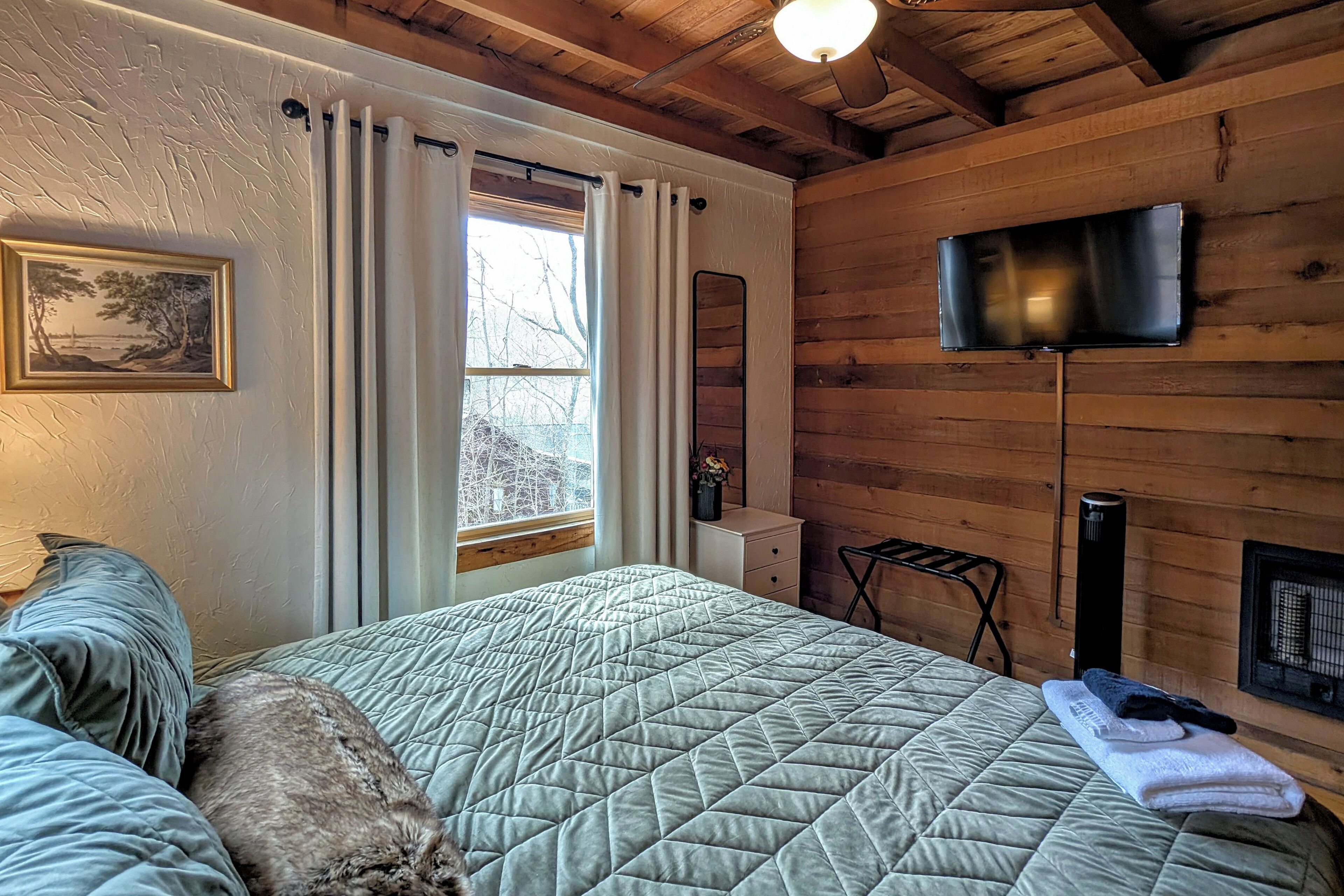 A cozy room with a bed, a TV, a heater, and a window with curtains.