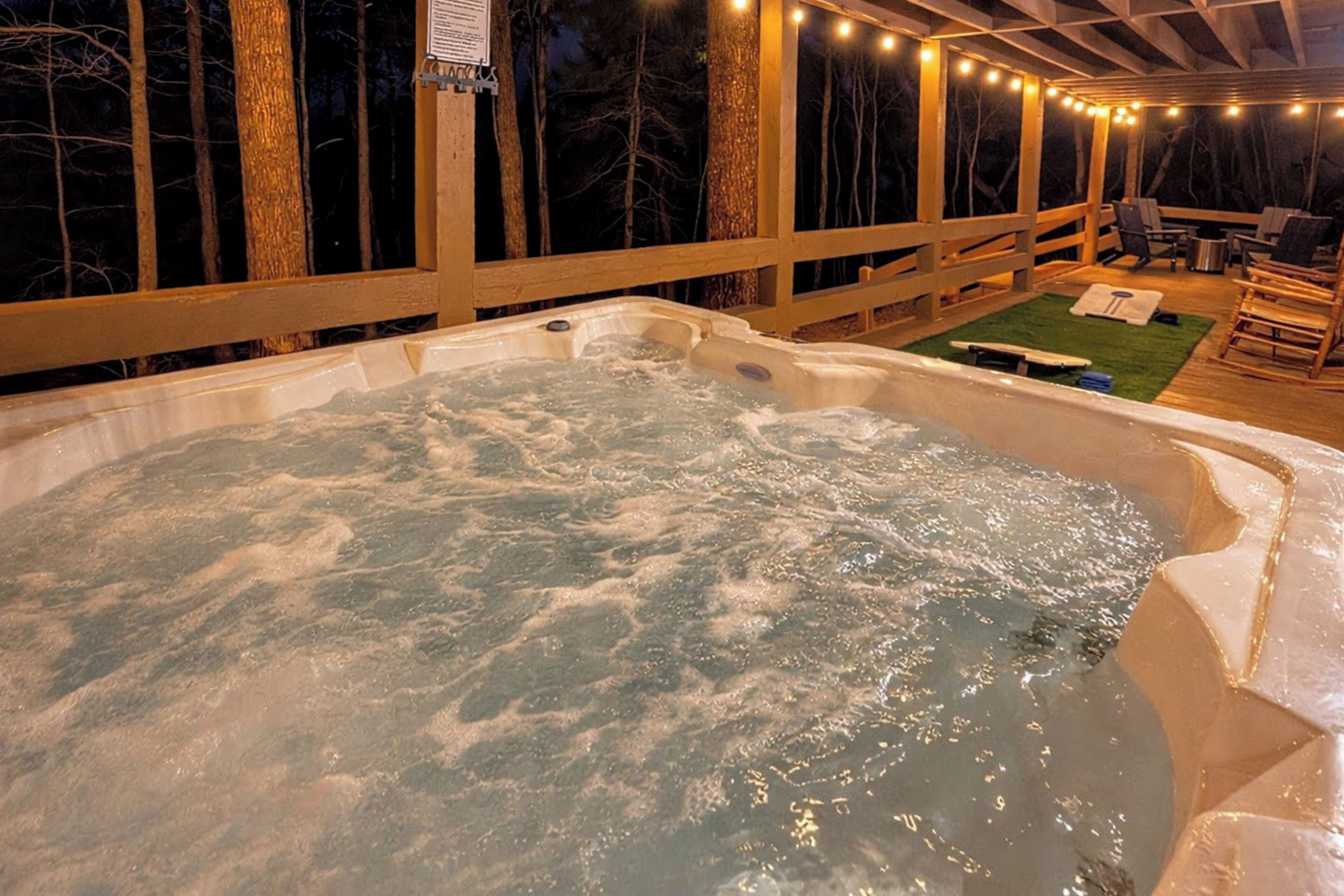 Una vasca idromassaggio con un molo in legno e luci decorative, immersa tra gli alberi.