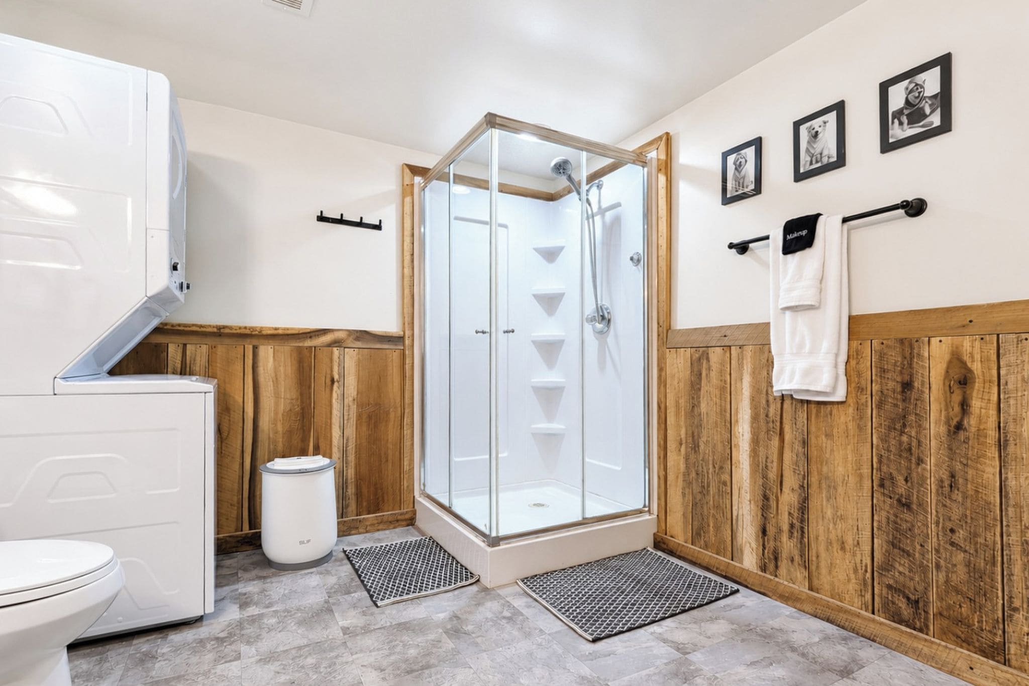 Een badkamer met een douchecabine, een toilet, een prullenbak en houten lambrisering.