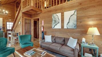 A wooden interior with a sofa, chairs, a coffee table, and artwork on the walls.