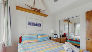 A bed with a colorful striped bedspread, a small bedside table with a lamp, a framed picture on the wall, and a sailboat model on the ceiling. - 5 Blocks to Shore! Rehoboth Beach Family Escape (Rehoboth Beach)