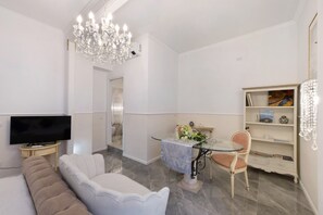 Un salon moderne avec un téléviseur, un canapé, une table en verre et des objets de décoration.