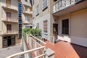 A residential building with multiple balconies, a tiled patio, and a door with a decorative wreath.