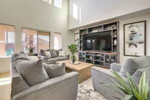 Ein Wohnzimmer mit grauem Sofa, Couchtisch, Fernseher und Bücherregal.