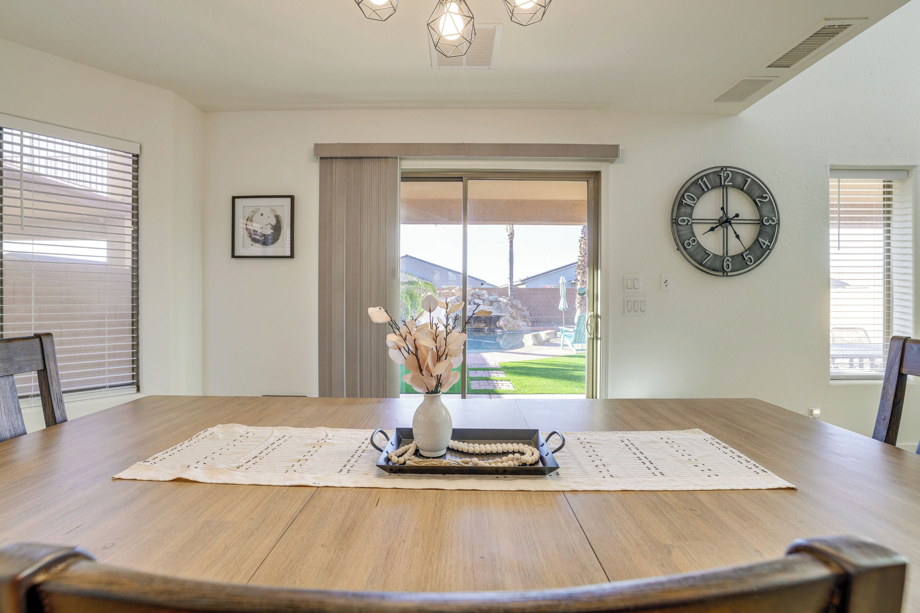 Ein Esszimmer mit Holztisch, einer Vase mit Trockenblumen und einer Wanduhr.