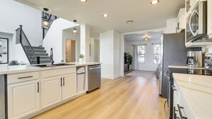 Una cocina moderna con armarios blancos, electrodomésticos de acero inoxidable y piso de madera.