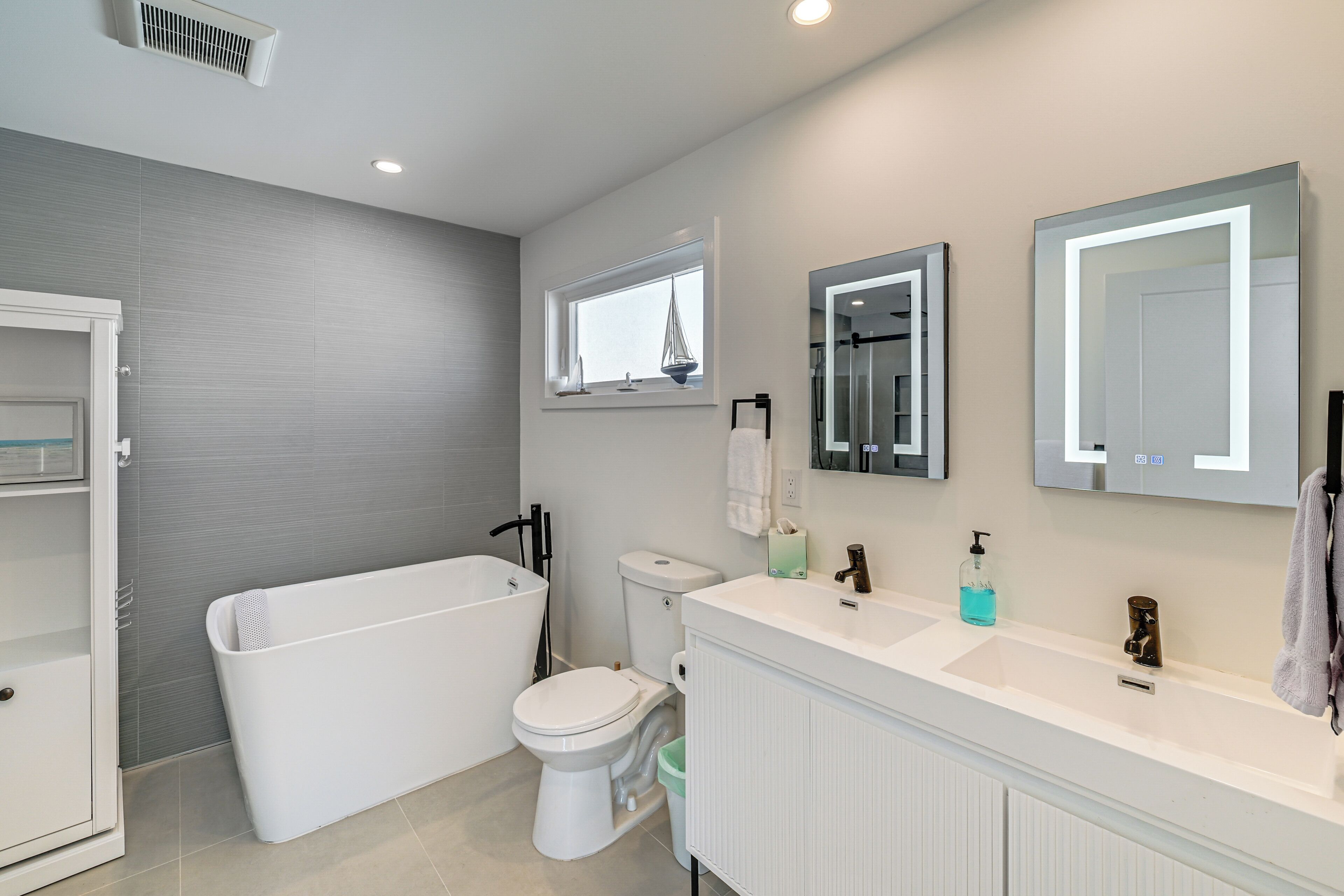Une salle de bain moderne équipée d’une baignoire, de toilettes et d’un meuble-lavabo avec un miroir.