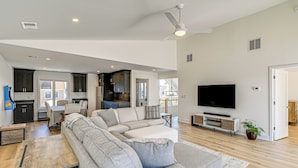 A spacious living room with a large sectional sofa, a flat-screen TV, and a dining area with a table and chairs. - Private Pool, Dock & Beach: Stafford Township Gem (Manahawkin)
