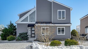 A two-story house with a grey exterior, a dark front door, and a small front yard with gravel and a few trees. - Private Pool, Dock & Beach: Stafford Township Gem (Manahawkin)
