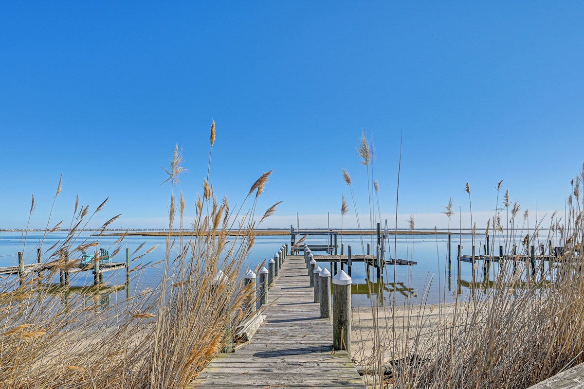 A wooden pier extending into calm water, surrounded by tall grasses.