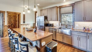 Une cuisine spacieuse dotée d’un grand îlot central, de meubles en bois, d’appareils électroménagers en acier inoxydable et de tabourets de bar.