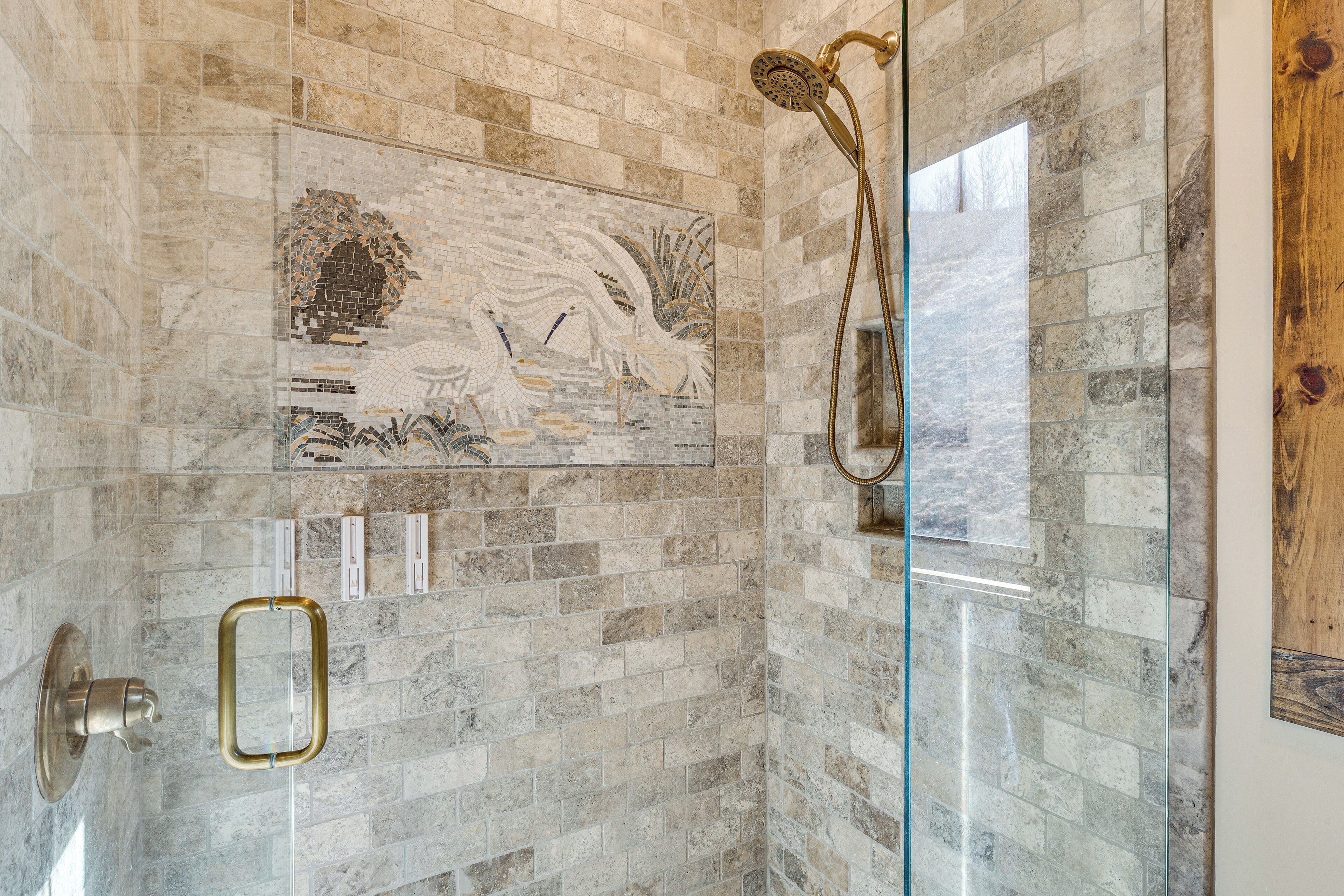 A bathroom with a glass shower enclosure, a decorative mosaic wall, and a wooden accent wall.