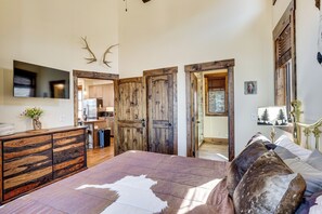 A bedroom with a large bed, wooden wardrobe, and a television on the wall. - A Piece of Heaven: Long Range Mtn Views All Year! (Banner Elk)