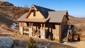 Une cabane en bois avec des fondations en pierre, une véranda et un escalier menant à l’entrée.