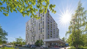 A multi-story hotel with a covered entrance and a parking area. - Functional Apartment with Balcony | Quiet Neighborhood (Kraków)