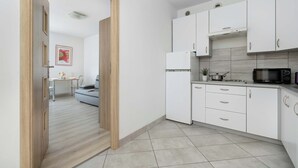 A modern kitchen with white cabinets, a microwave, and a refrigerator. - Functional Apartment with Balcony | Quiet Neighborhood (Kraków)