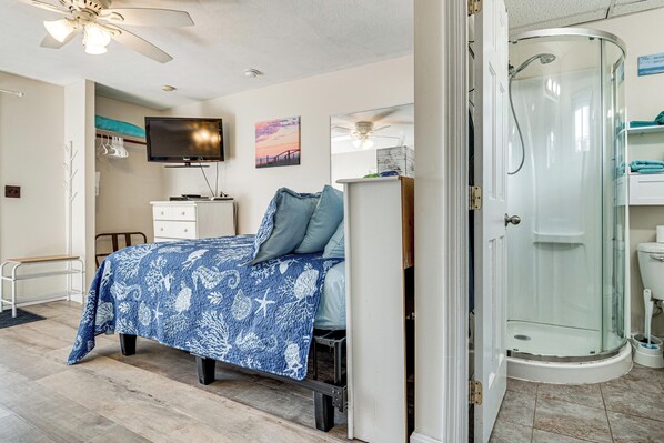 Une chambre avec un lit, une télévision, un bureau et une douche.