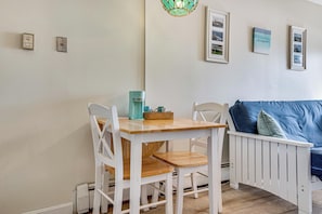 A room with a wooden table and white chairs, a teal coffee maker, and a blue sofa with cushions. - Steps to Sandy Beach! Oceanfront Old Orchard Gem (Old Orchard Beach)