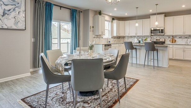 A modern kitchen with white cabinets, a central island, and a dining area with a round table and chairs. - 2 Mi to National Sports Center: Blaine Base Camp (Blaine)