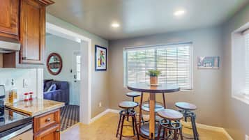 A kitchen with a central island, bar stools, a built-in oven, and a window with blinds.