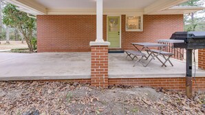 Un patio abrité avec un mur en briques, une porte verte et un barbecue.
