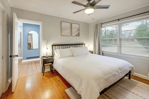 A bedroom with a bed, a ceiling fan, a nightstand, and a window with blinds. - Updated + Inviting! North Macon Home Near Dtwn (Macon)