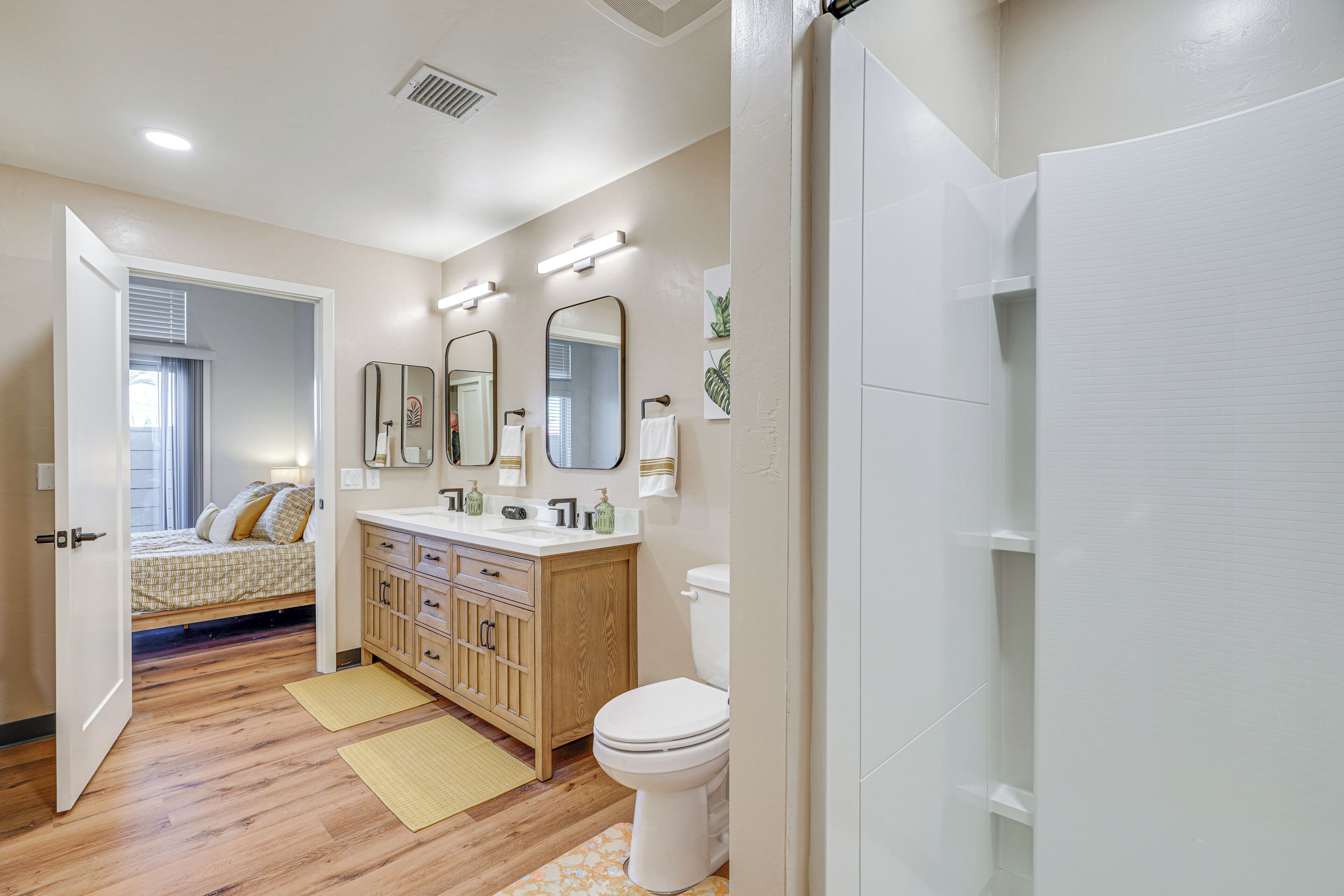 A bathroom with a toilet, vanity, mirrors, and a shower area.