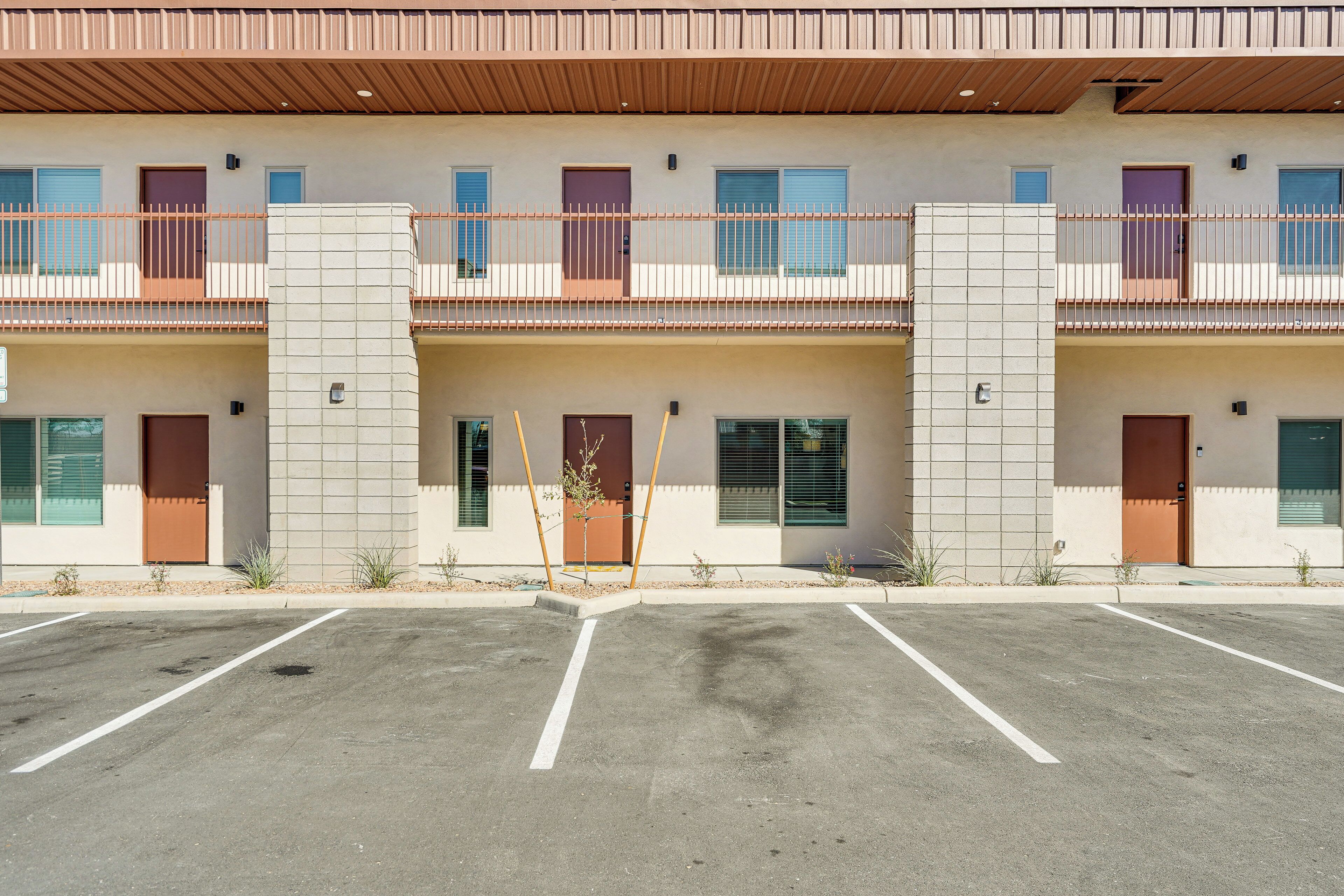 A multi-story hotel with a flat roof, balconies, and a parking lot.