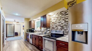Cozinha moderna com eletrodomésticos de aço inoxidável, armários de madeira e backsplash com padrão.